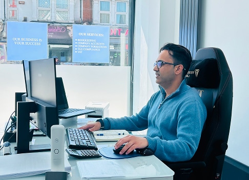 Contractors seated at a desk, working on two computers.