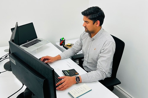 ARB Accountant seated at a desk, working on two computers, focused on bookkeeping services
