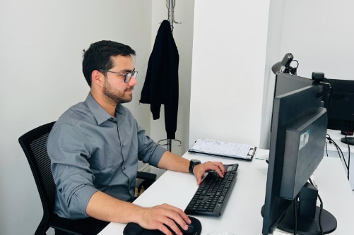 A man in a gray shirt sits at a desk, focused on his work with UK incorporation