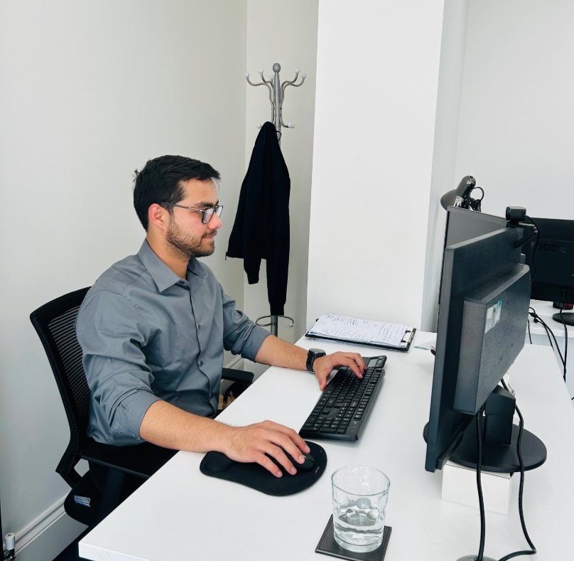 Accountant in a gray shirt sits at a desk, focused on auto enrolment services