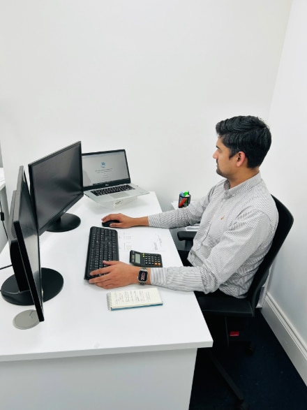 A man seated at a desk, working on budgeting and forecasting services