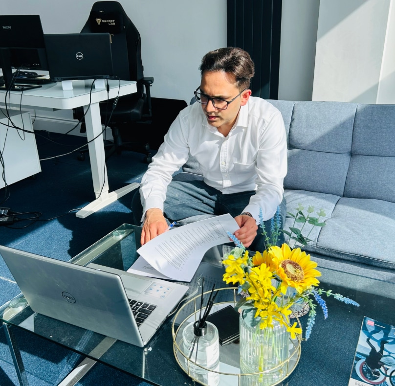 Man wearing glasses sits at a desk with a laptop working on payroll outsourcing services
