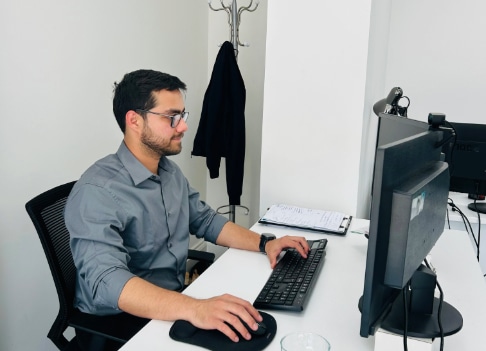 A man in a gray shirt sits at a desk, focused payroll management services