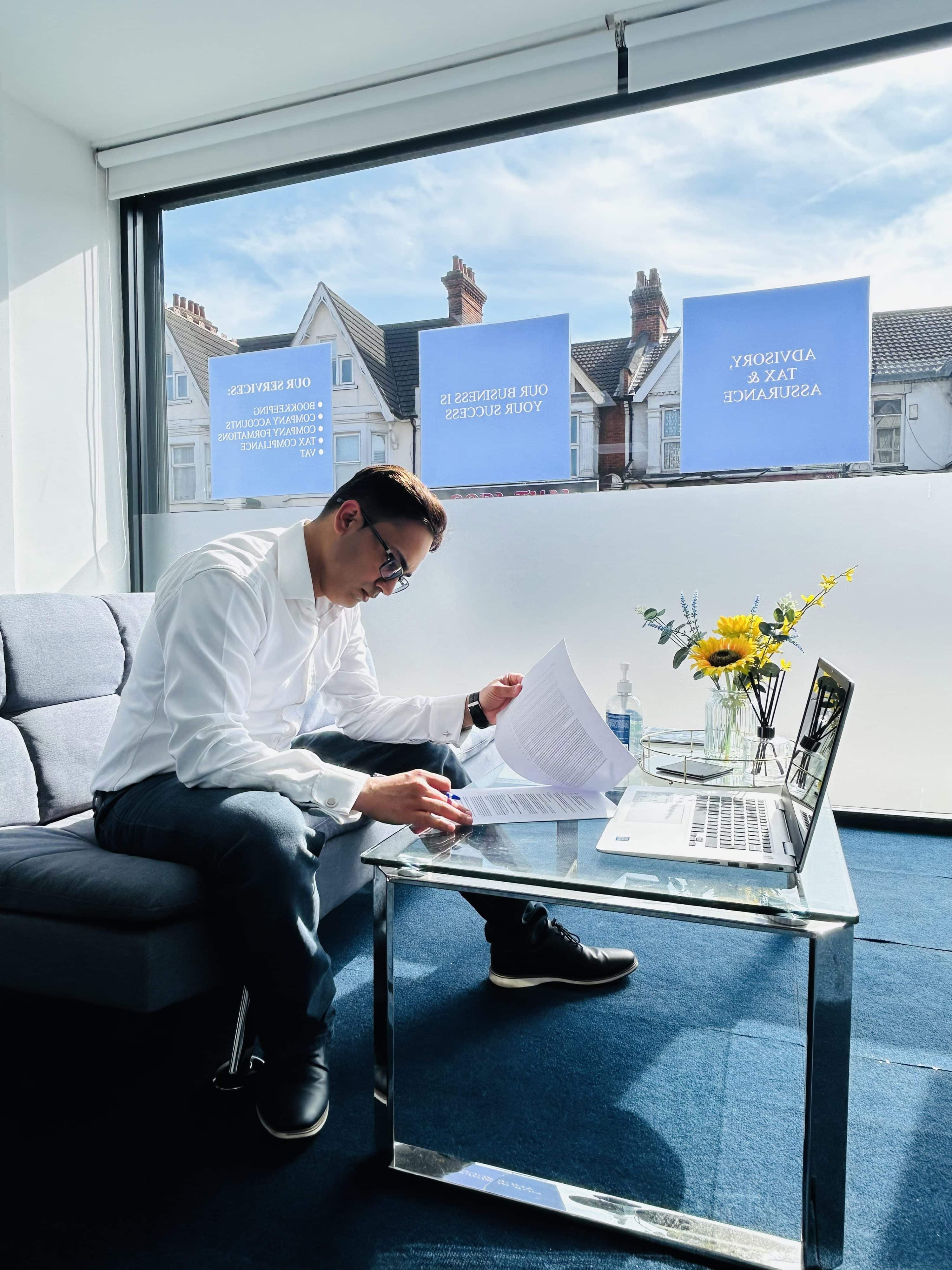 Tax audit UK Man wearing glasses sits at a desk focusing on tax audit UK