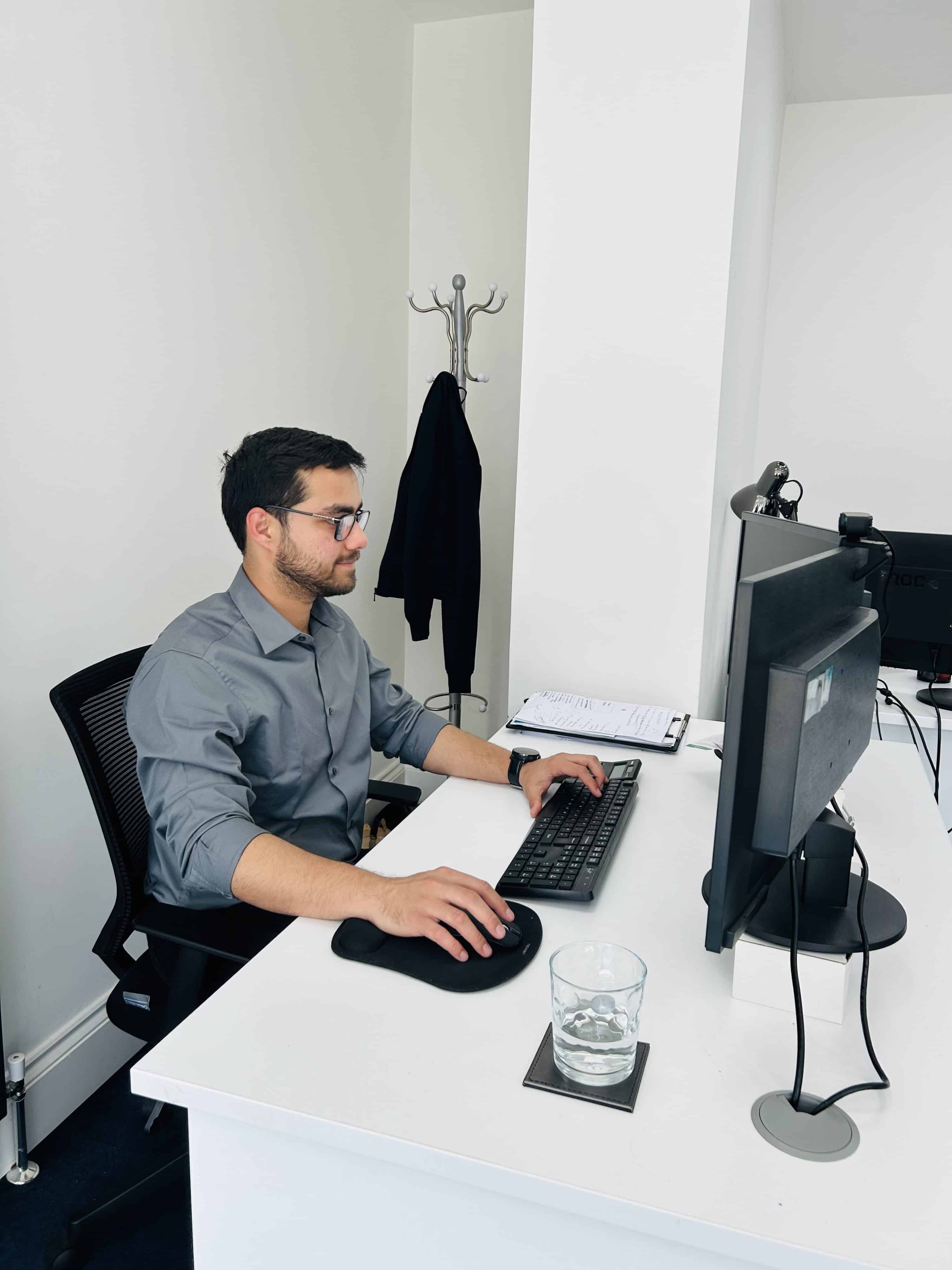 A man in a gray shirt sits at a desk, focused on corporate tax advice