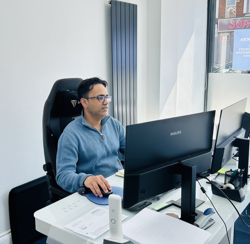 Saurabh Bedi seated at a desk, working on two computers, focused on preparation of management accounts