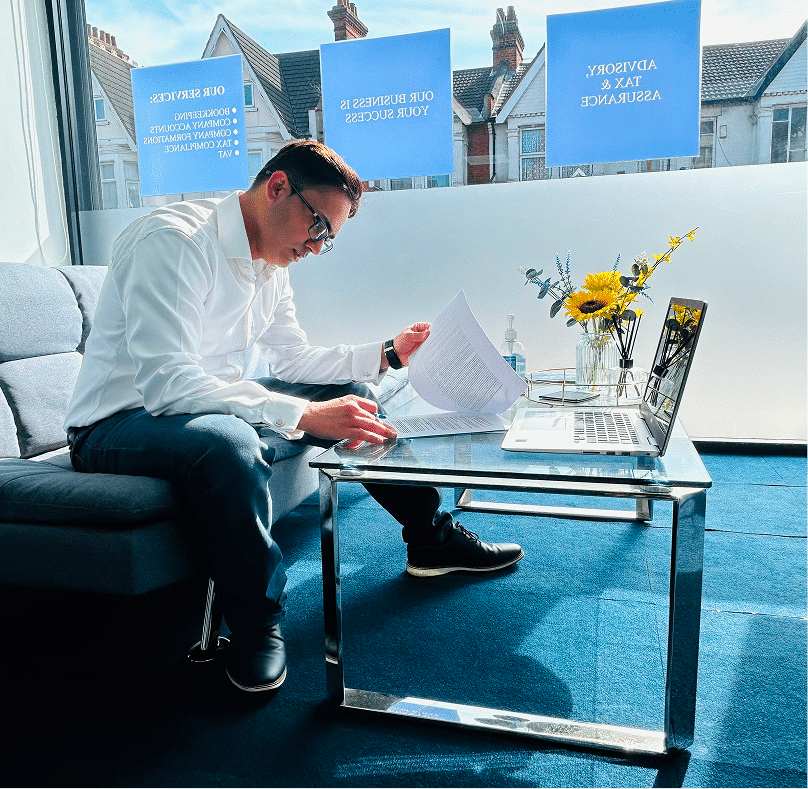 Man wearing glasses sits at a desk giving personal tax advice UK
